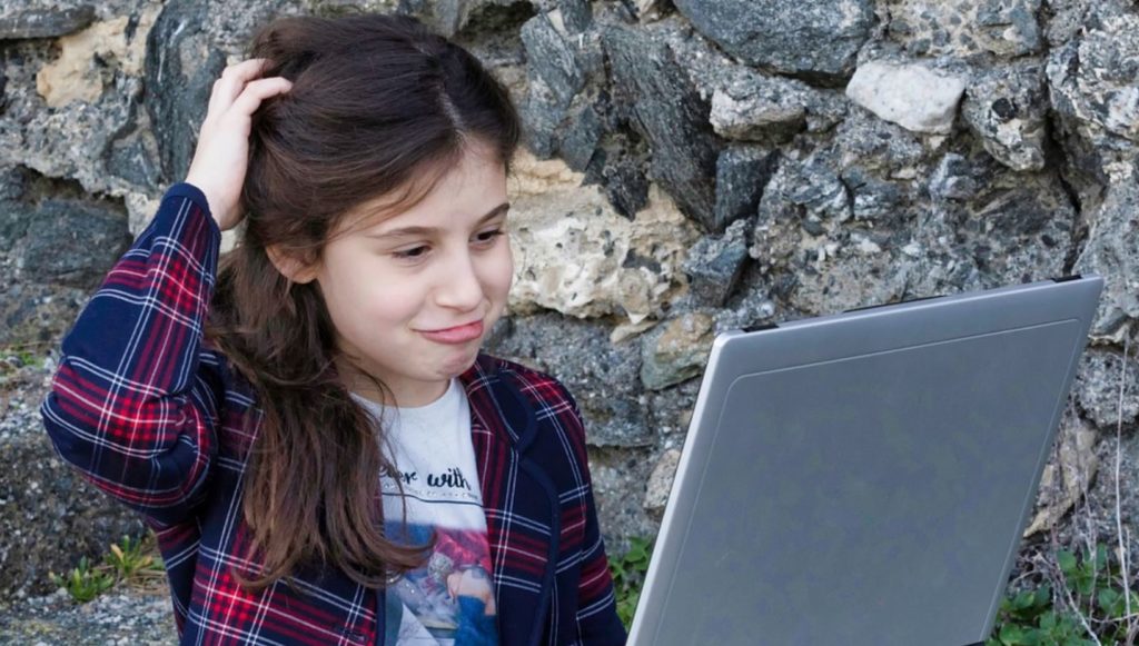 Young girl frowns at her computer.